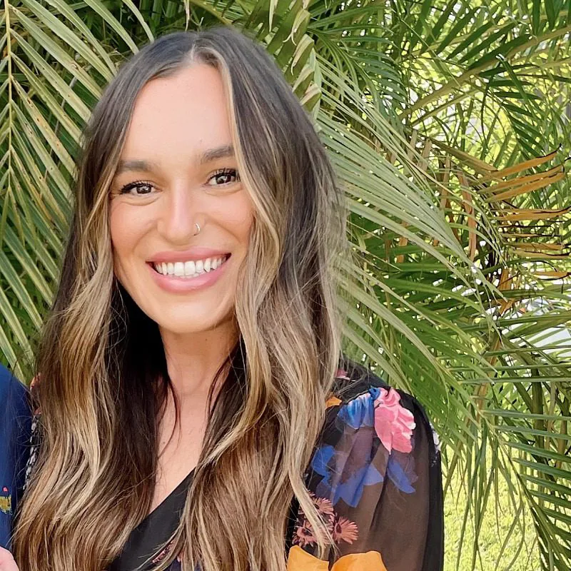 Maria C - female with long brown wavy hair wearing a floral blouse