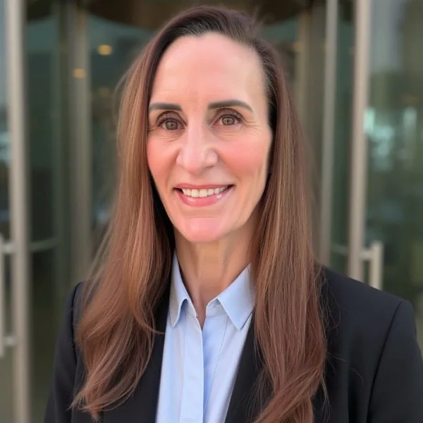 Shannon Labrie - female with long dark hair wearing a blue button up shirt and a dark blazer